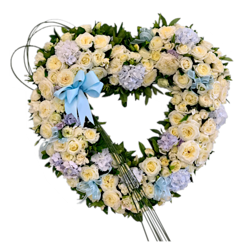 Heart shaped funeral wreath is created from a range of handpicked seasonal flowers including roses of varying sizes and carnations in full bloom. Shades of white, blue and purple decorate this touching display.